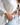 woman wearing gold bangle bracelets, light blue jeans and a white shirt with ties in the front.  