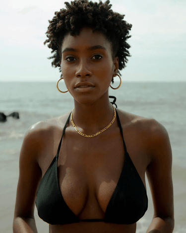 woman at the beach wearing a gold figaro chain and medium sized hoop earrings