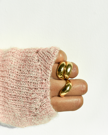 person wearing pink sweater and 3 BEN ONI gold cameron wave rings stacked on multiple fingers. 